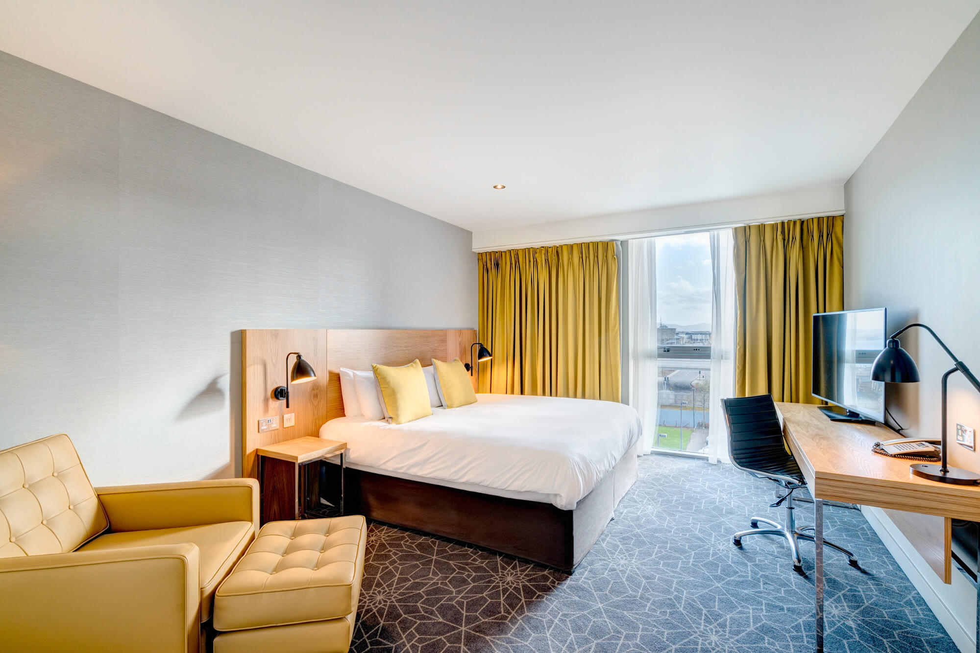 King-size bed with armchair and desk with TV